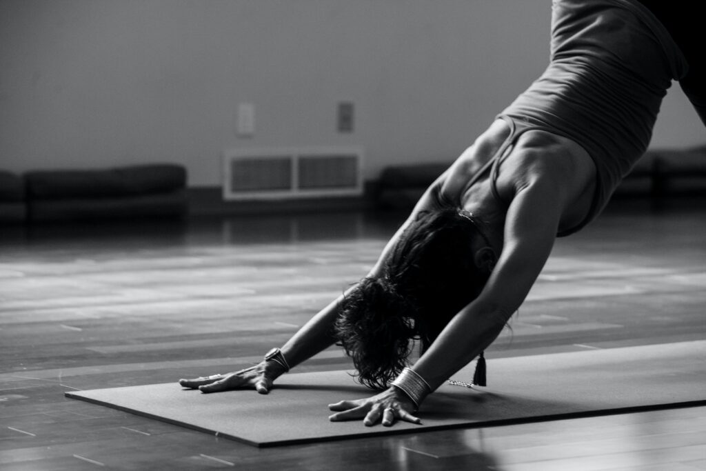 Woman in the pose downward facing dog, in black and white.